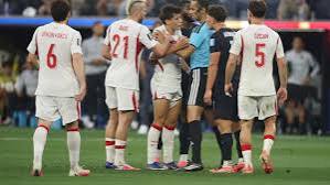 Türkiye and USA Players Clash with Referee in World Cup Drama (15) Turkish national football team players including Orkun Kökçü (6) and Salih Özcan (5) argue and confront the referee alongside a USA player during a tense match moment.