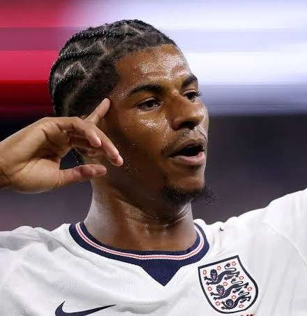 images (1)Marcus Rashford Pointing to His Head in Celebration A close-up shot of professional soccer player Marcus Rashford wearing a white England national team kit, looking off-camera and pointing his index finger to his temple in his signature celebration. He has braided hair and a slight goatee.