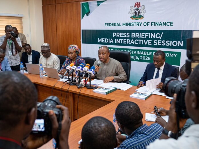Ministry of Finance World Bank debt claim press briefing in Abuja with officials addressing journalists behind multiple microphones.