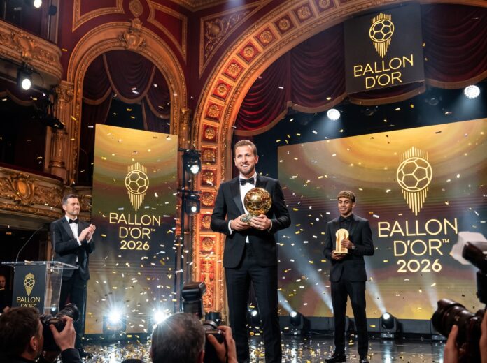 Bayern Munich striker Harry Kane proudly holding his golden trophy on stage alongside Lamine Yamal during the historic Harry Kane Ballon d'Or 2026 ceremony.