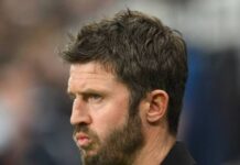 Manchester United crisis Lisandro Martinez fallout showing Michael Carrick looking tense and focused with a concerned side profile expression on the touchline.
